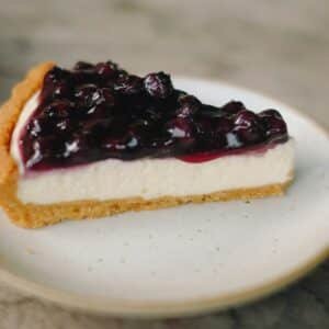 slice blueberry cheesecake pie on white ceramic plate